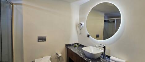A modern bathroom with a toilet, sink, and mirror.