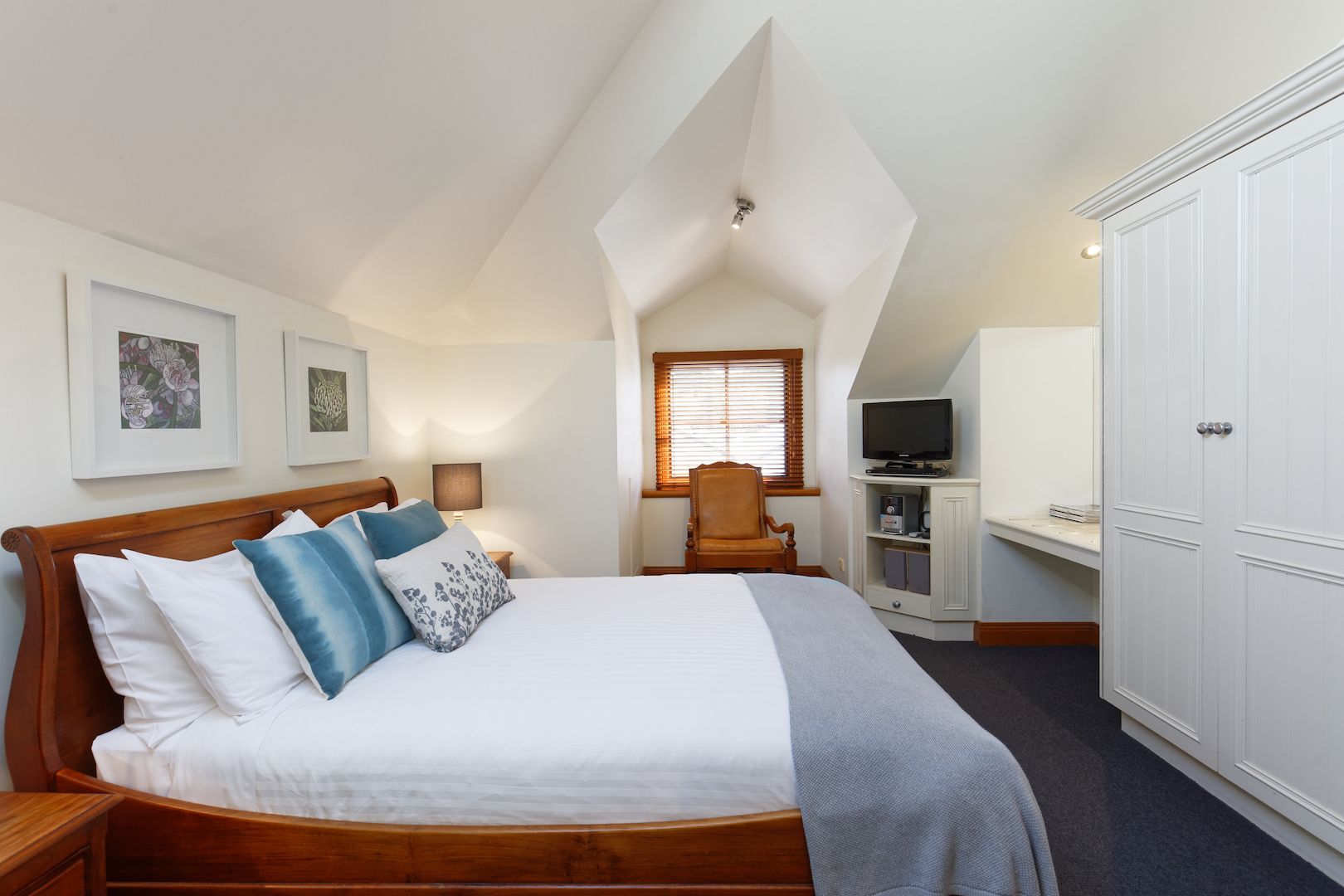 A bedroom with a bed, a chair, a TV, and a wardrobe.