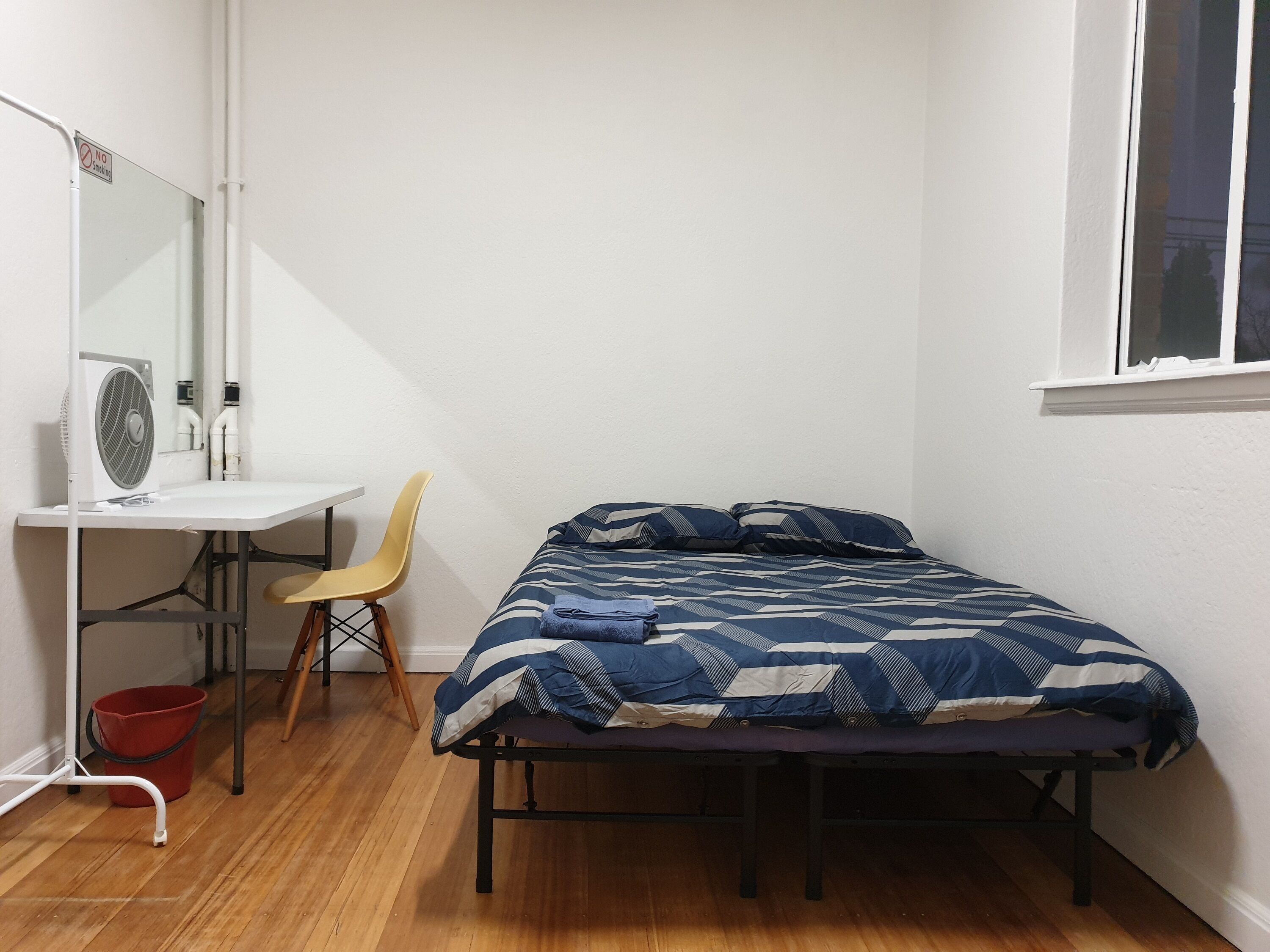 A bedroom with a bed, a desk, a chair, and a window.