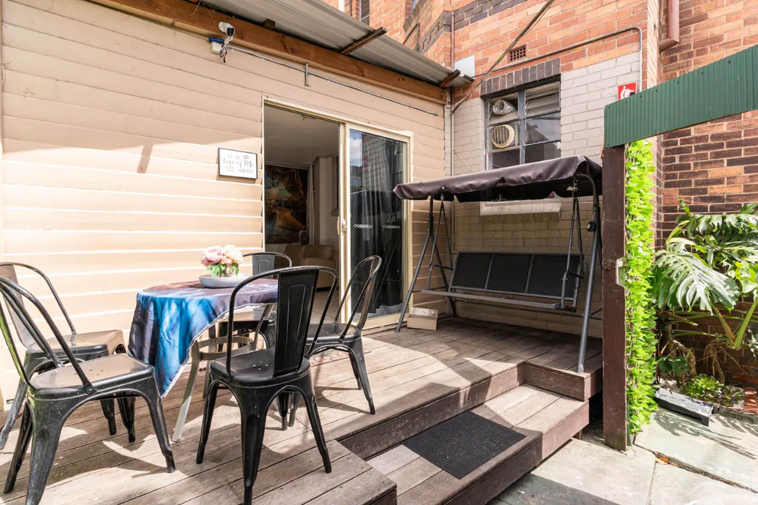 A patio area with a table and chairs, a barbecue grill, and a small garden.