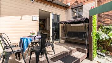 A patio area with a table and chairs, a barbecue grill, and a small garden.