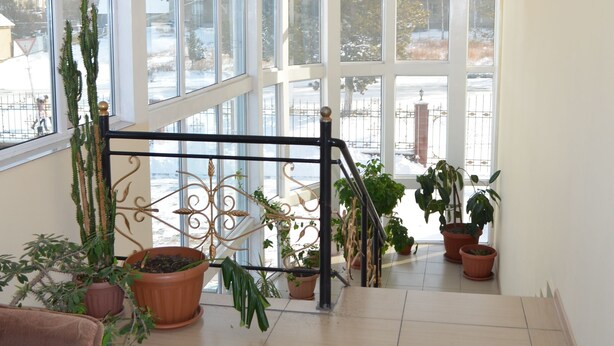 A spacious room with large windows, a staircase, and potted plants. - Altamira (Karakol)