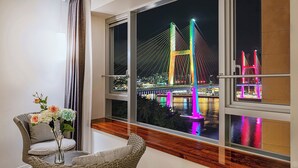 Una habitación con un amplio ventanal que da a un puente iluminado de noche.