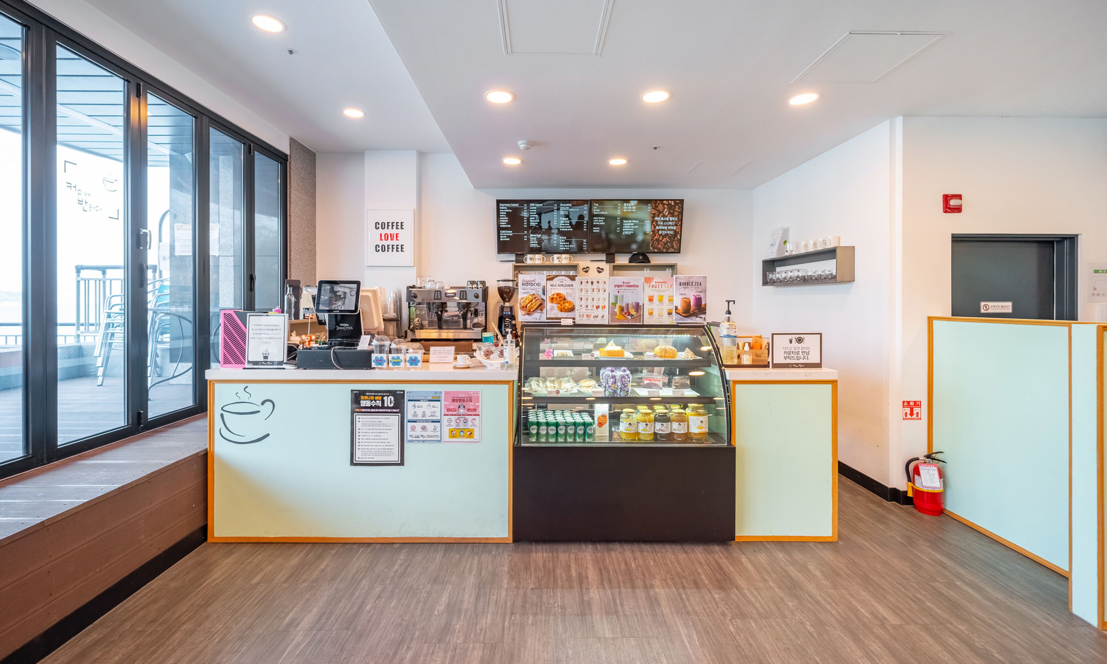 Interior de una cafetería con mostrador, menú y vitrina.