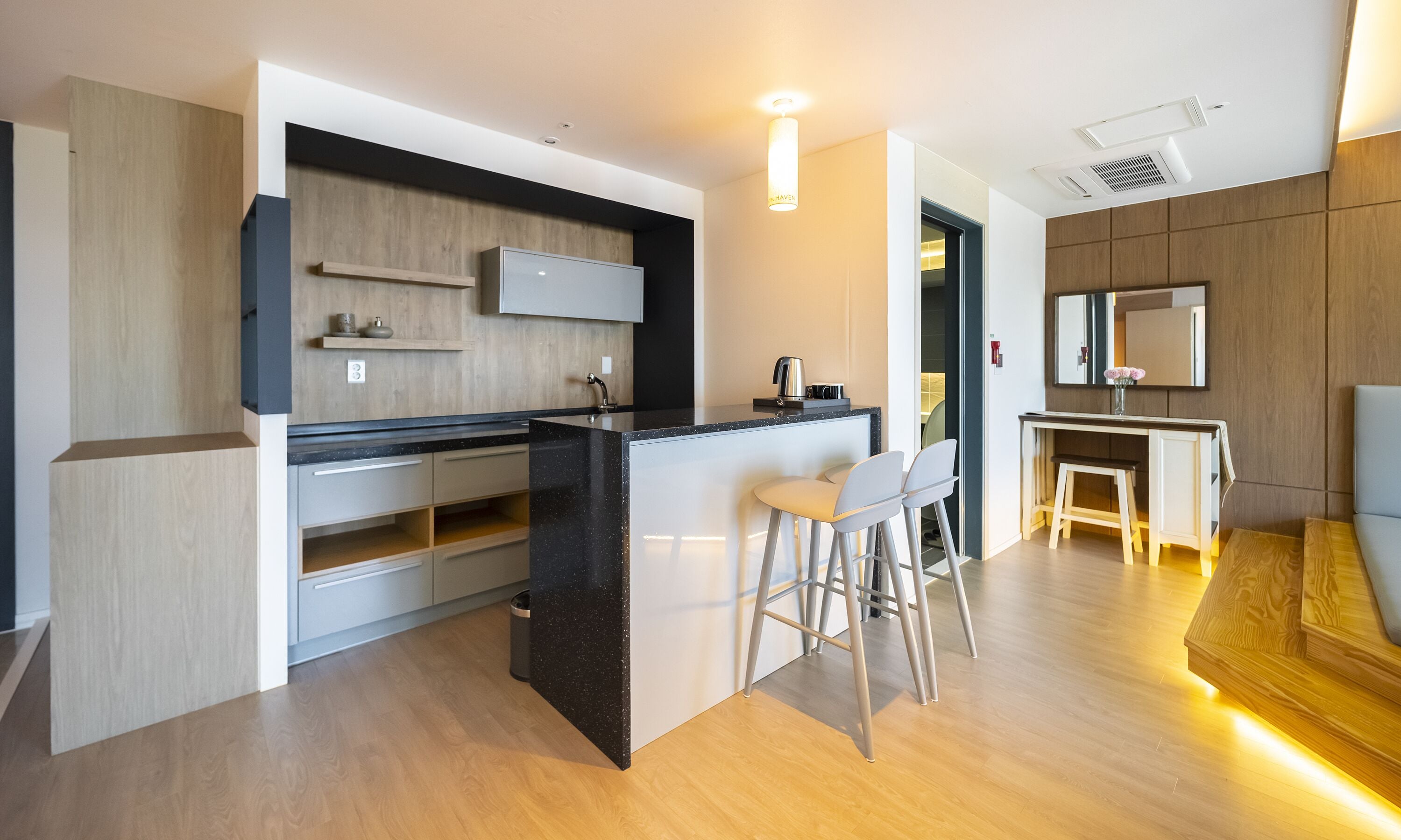 A modern kitchen with a central island, bar stools, and a dining area with a small table and chairs.