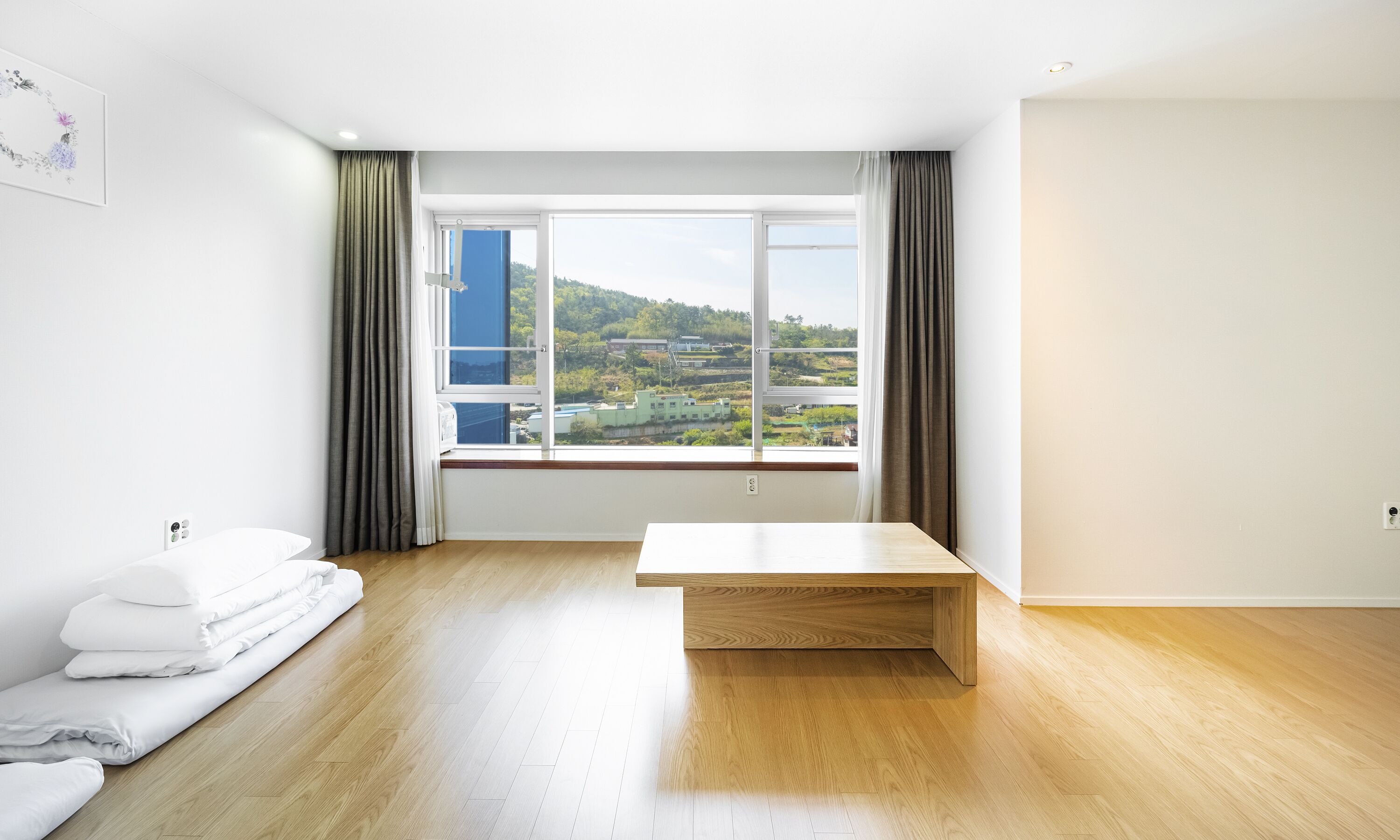 A modern room with a large window, a wooden bench, and a neatly made bed.