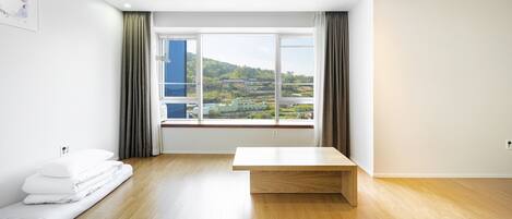 A modern room with a large window, a wooden bench, and a neatly made bed.