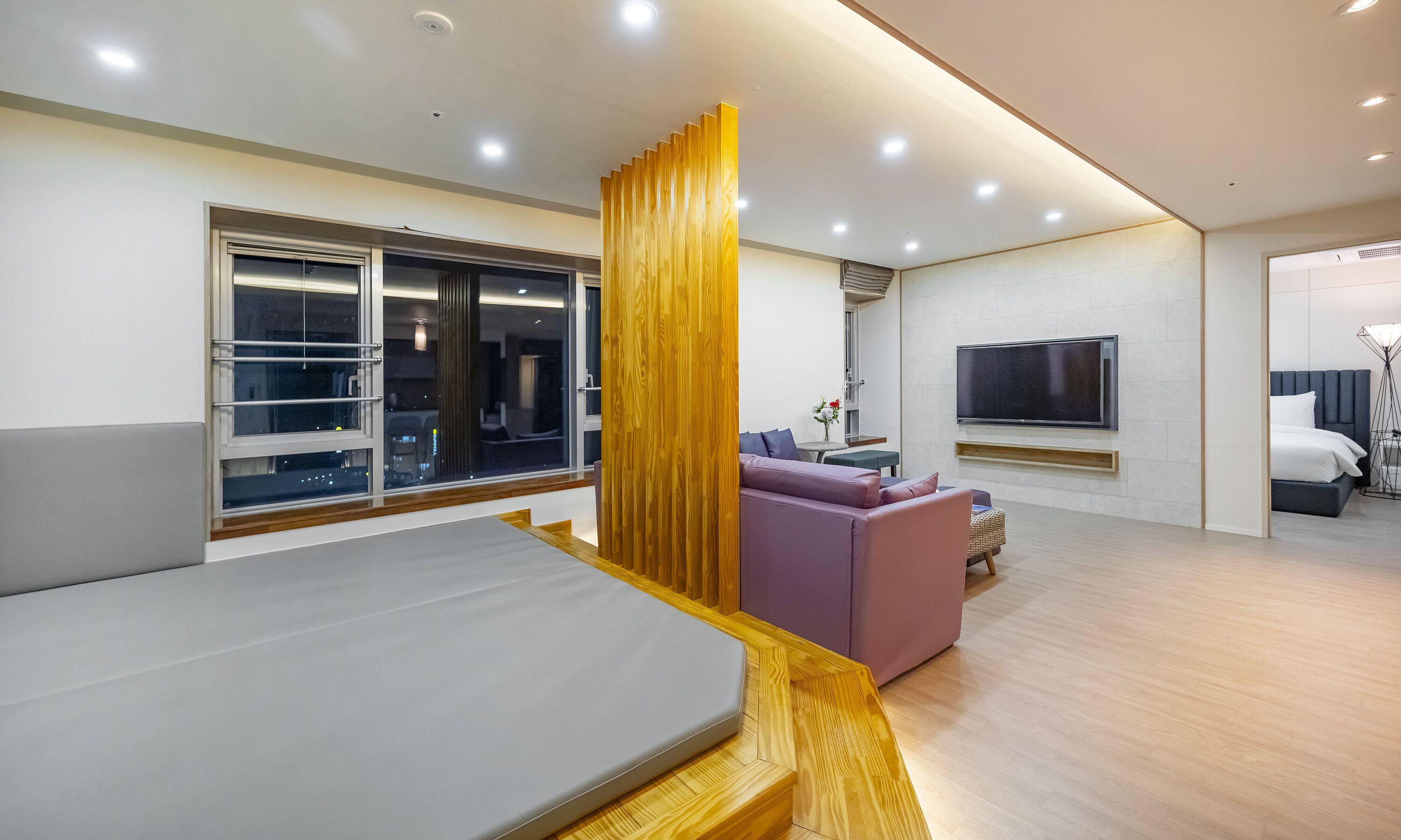 A modern living room with a sofa, a TV, and a bed.