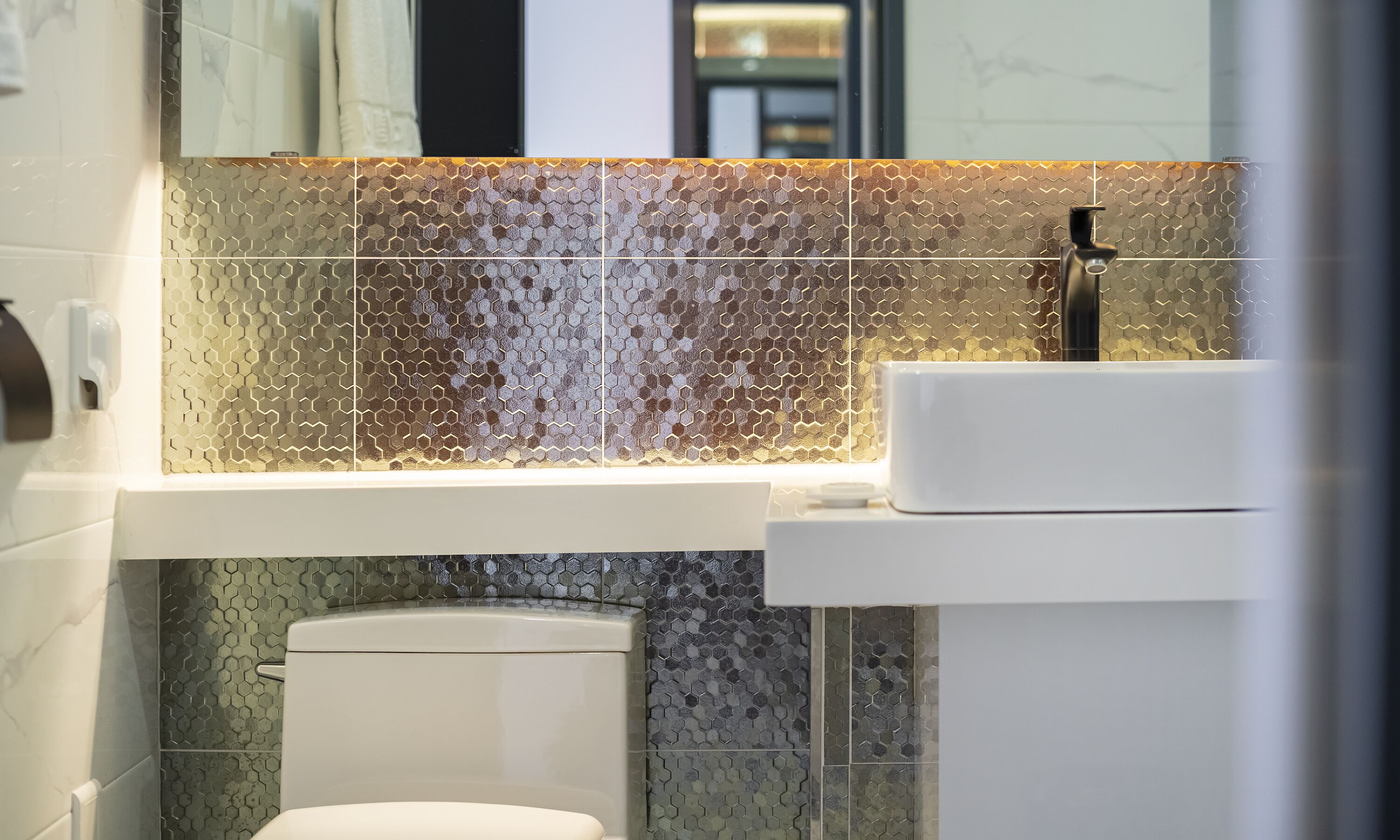 Un baño moderno con inodoro, lavamanos y espejo.