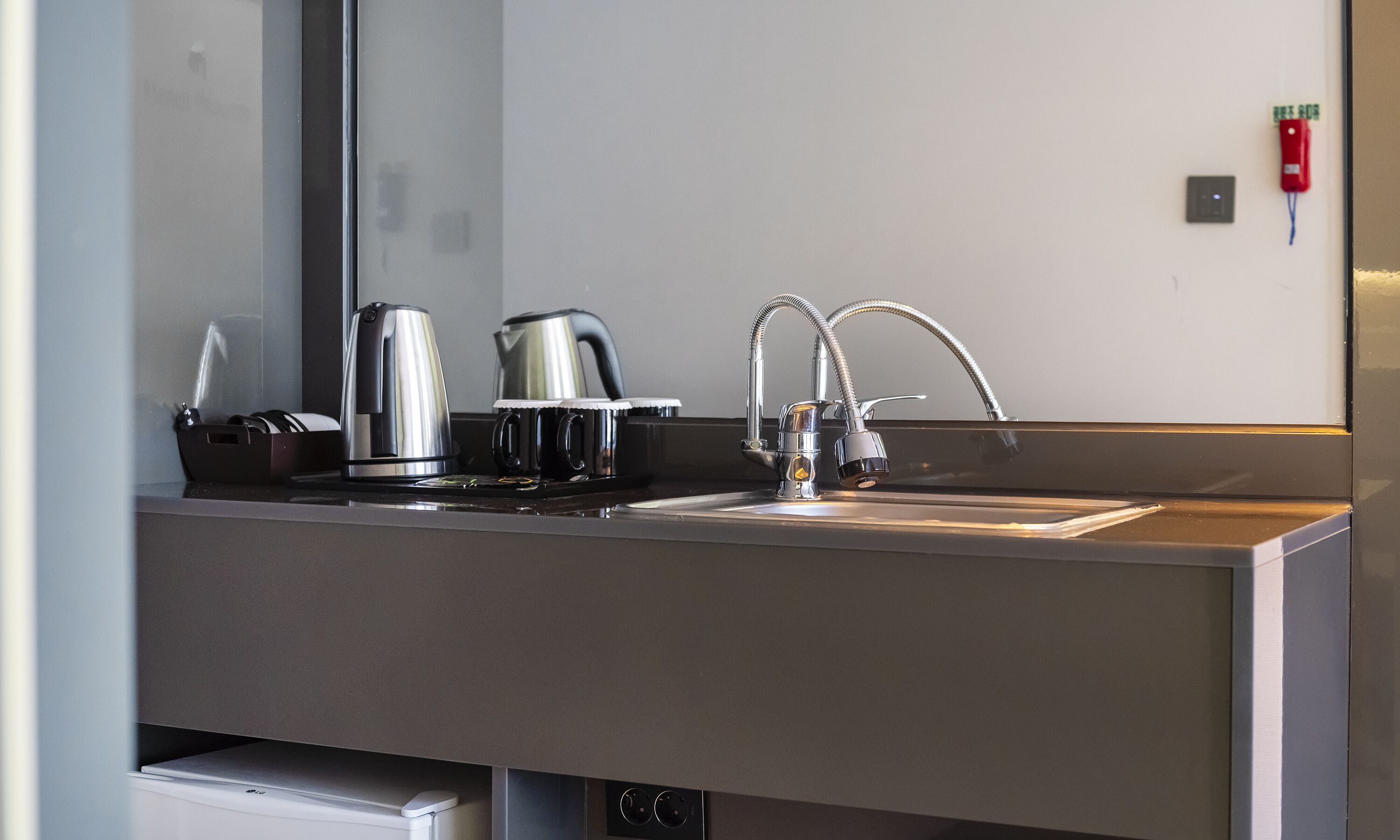 A modern kitchen with a stainless steel sink, a kettle, and a coffee maker.