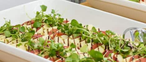 A white rectangular dish with a layered salad on a wooden table.