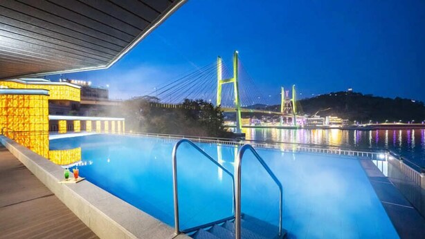 Piscina con vista a un puente y un paisaje urbano de noche.