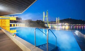 A swimming pool with a view of a bridge and a cityscape at night. - Hotel Haven (Yeosu)
