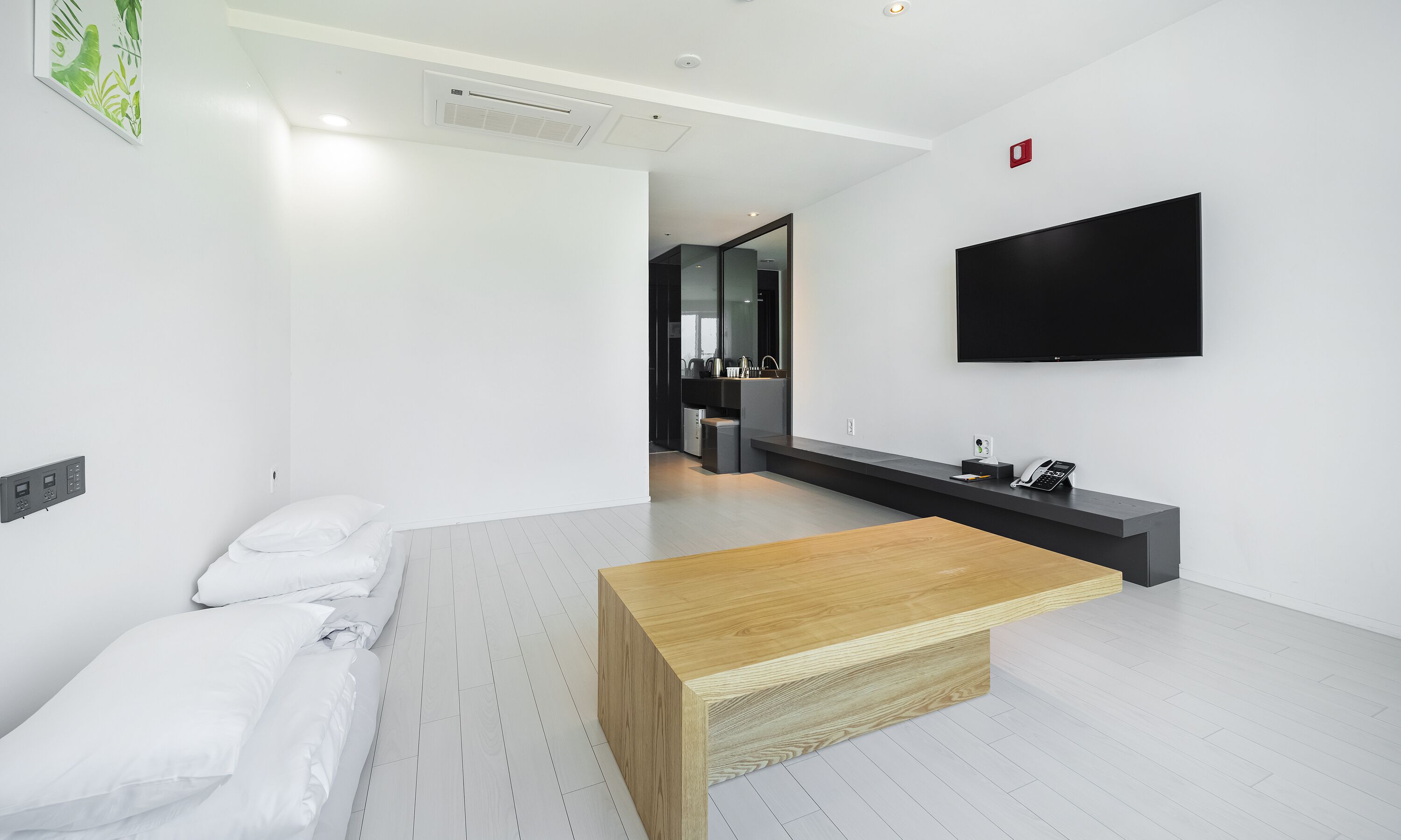 Een moderne hotelkamer met een houten bijzettafeltje, wit beddengoed, een flatscreen televisie en een minimalistisch design.
