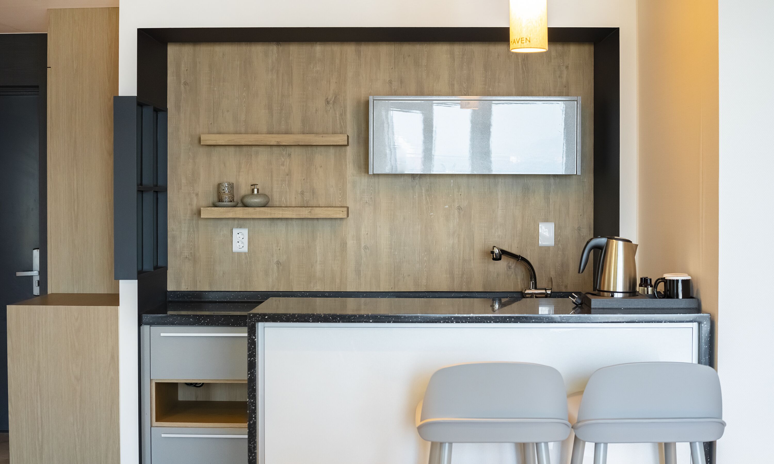 Une cuisine moderne avec un revêtement mural en bois, un évier en acier inoxydable et deux tabourets de bar.