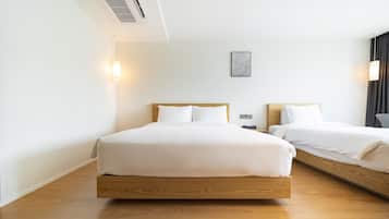 A hotel room with two beds, wooden headboards, white linens, a wall-mounted light fixture, and a framed artwork.
