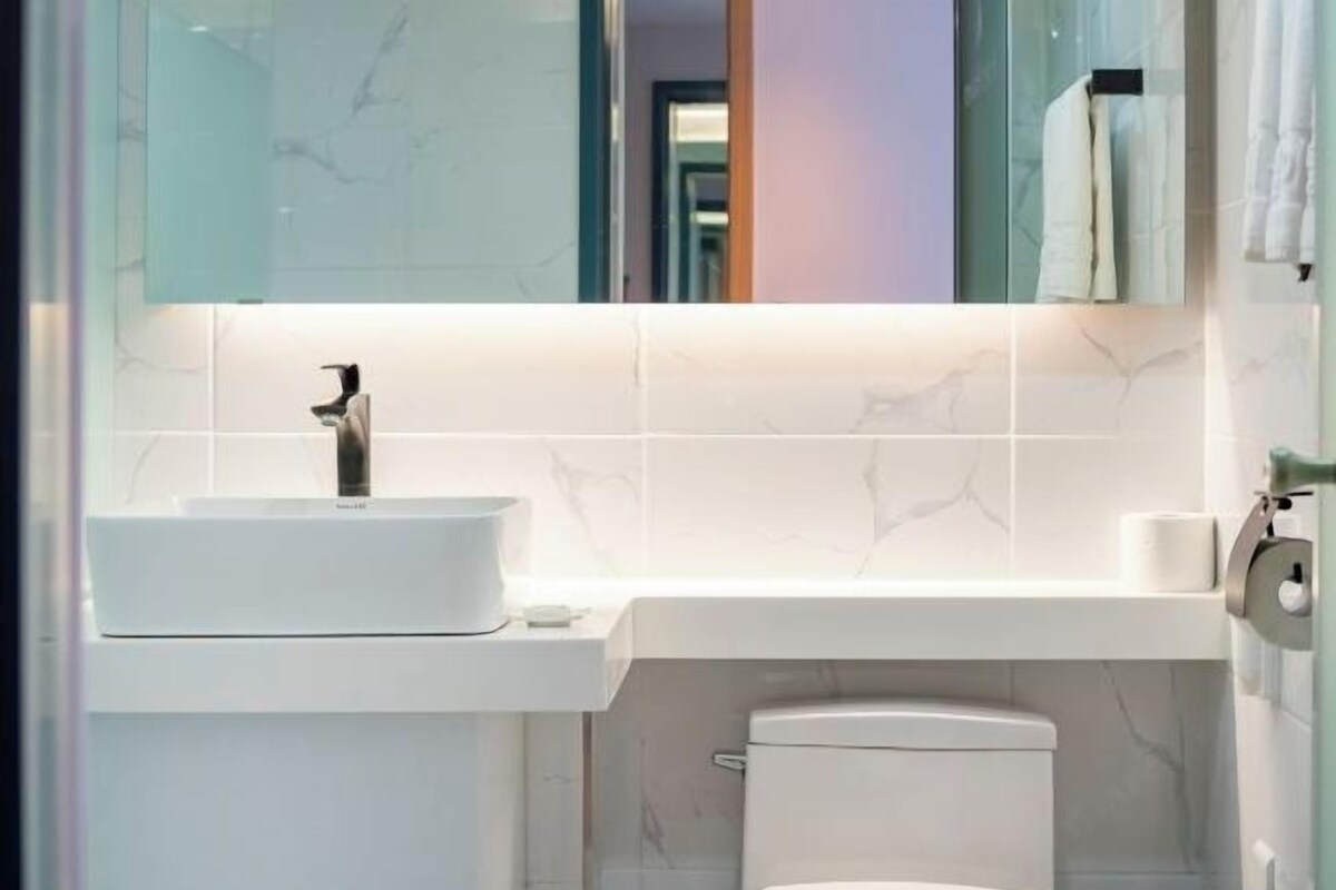A modern bathroom with a white sink, a toilet, and a mirror above the sink.