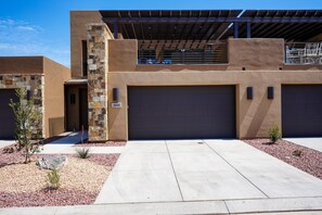 A modern building with a stone facade, two garages, and a covered patio area.