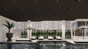 A modern indoor pool area with lounge chairs and umbrellas, surrounded by potted plants and a patterned wall. - Floral Hotel Chaweng Koh Samui (Koh Samui)