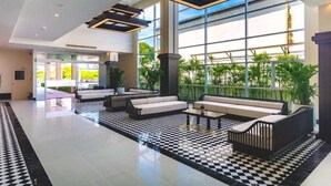 A spacious lobby with a checkered floor, modern seating areas, large windows, and a view of greenery outside. - Floral Hotel Chaweng Koh Samui (Koh Samui)