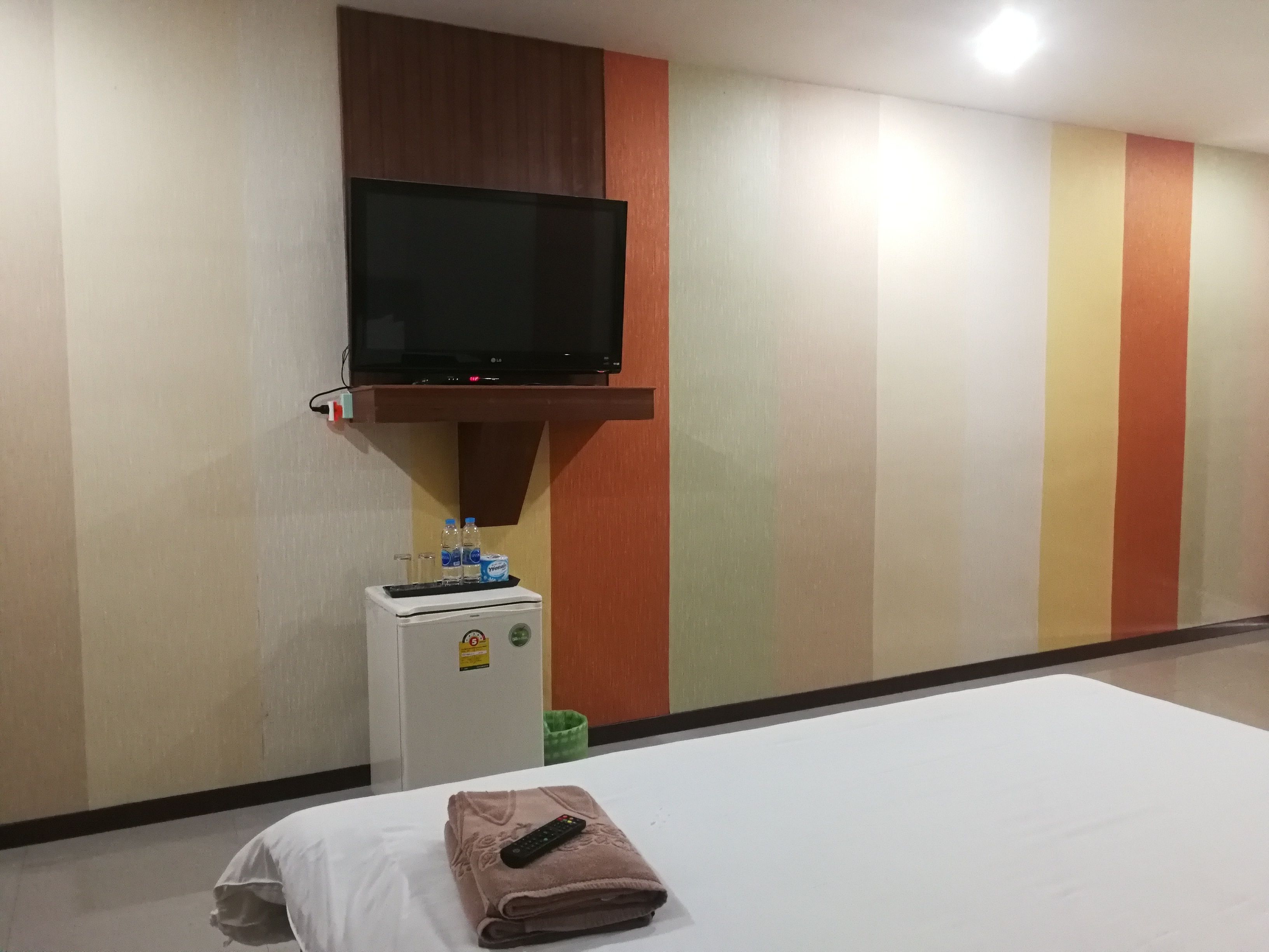 Ein Hotelzimmer mit Bett, Wandfernseher, Minikühlschrank und Wasserspender.