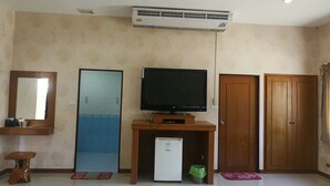A room with a television on a wooden stand, a small refrigerator, a mirror, and a door. - Reurn Thai Resort Ratchaburi (Damnoen Saduak)