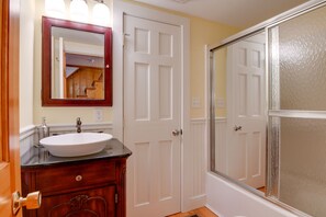 A bathroom with a white sink, wooden vanity, and a mirror with lights. - North Conway Home: Walk to Cranmore Mtn Resort! (North Conway)