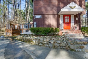 A cabin with a stone foundation, wooden deck, and a red door. - North Conway Home: Walk to Cranmore Mtn Resort! (North Conway)