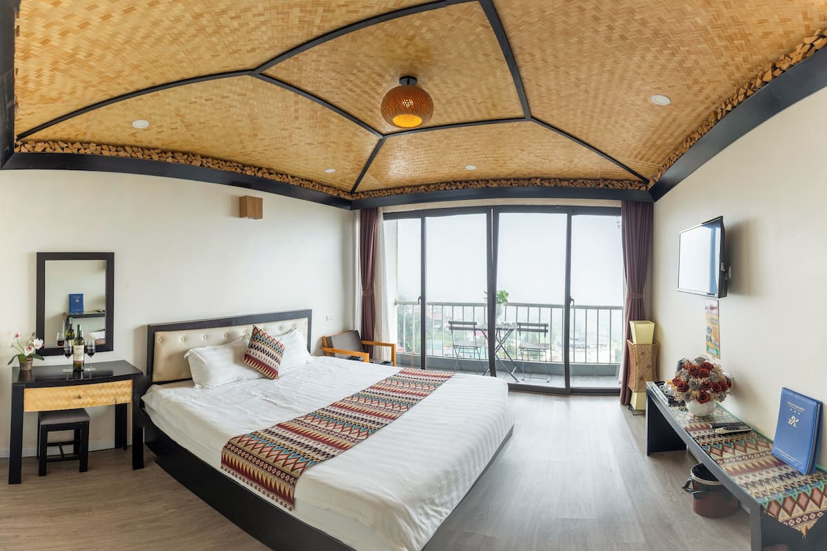 Een hotelkamer met een groot bed, een bureau, een stoel, een televisie en een balkon met uitzicht.