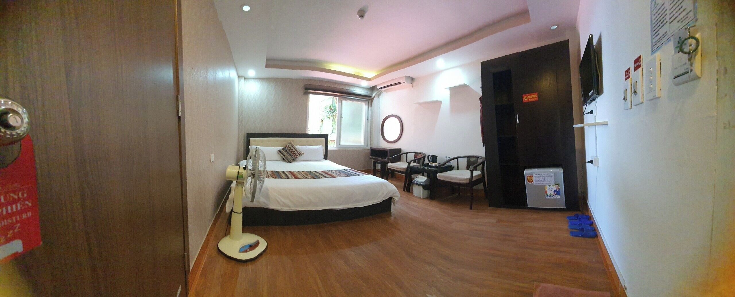 A hotel room with a bed, bedside table, chair, and a small desk with a chair.