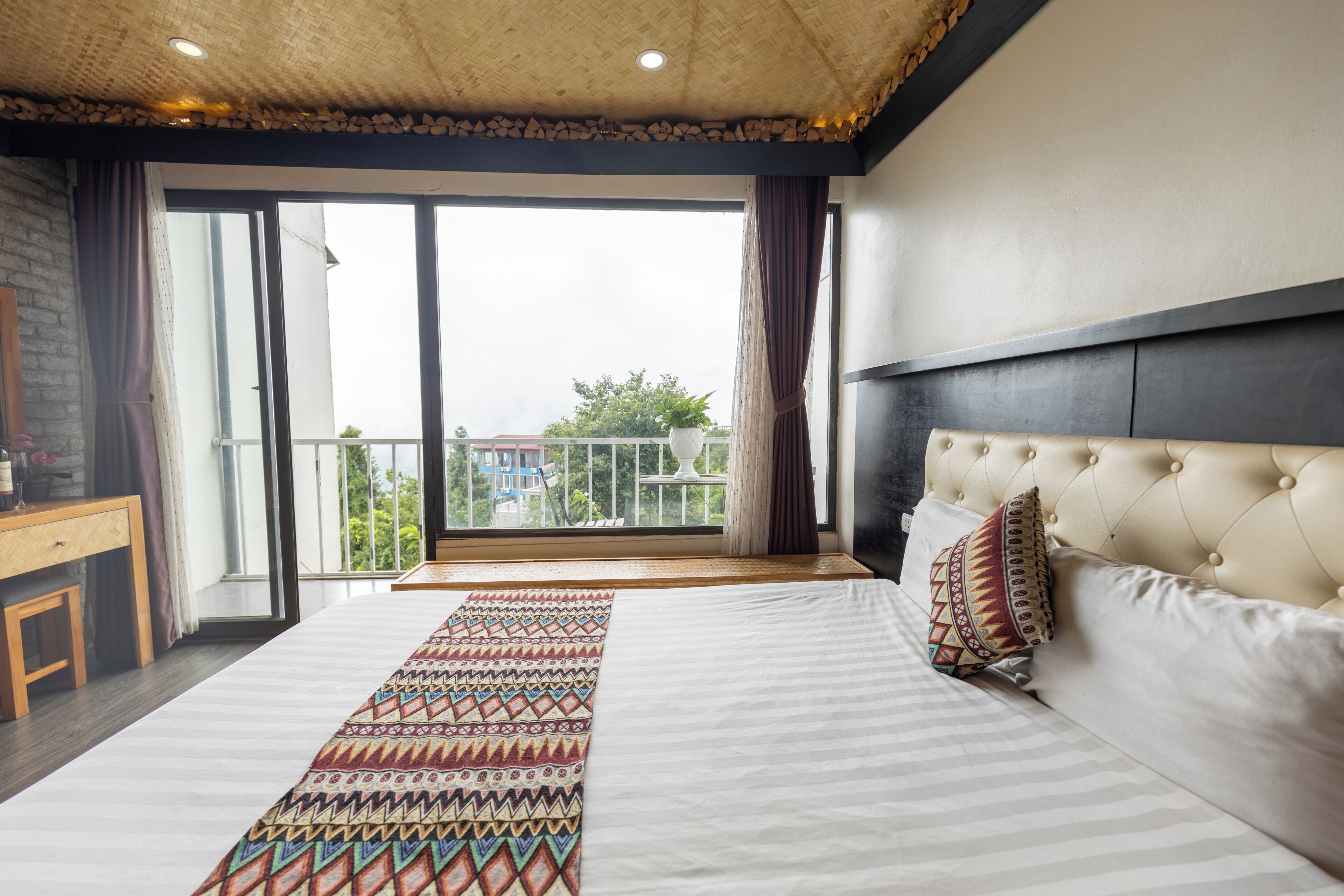A bedroom with a large bed, a view of the outside, and a balcony.