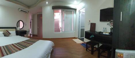 A hotel room with a bed, a desk, a television, and a window.