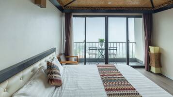 A hotel room with a large bed, a balcony with a table and chairs, and a view of the city.