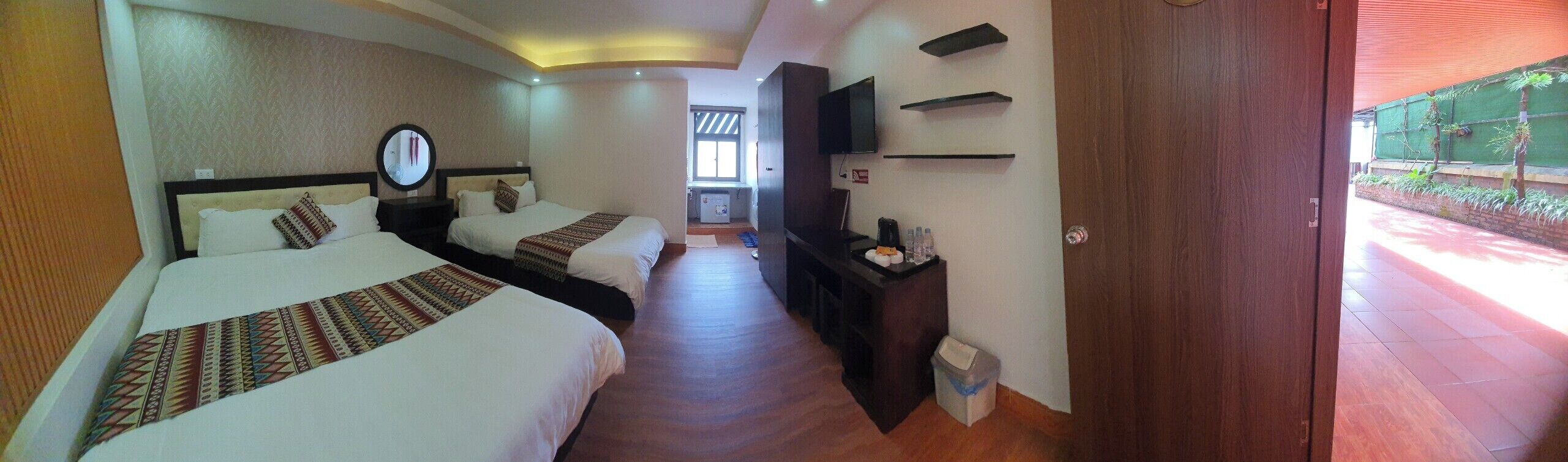 Habitación de hotel con dos camas, un televisor, una mesita y un cubo de basura.