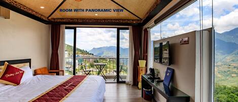 A room with a panoramic view, featuring a large bed, a desk, and a television.