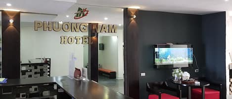 Un área de recepción con mostrador, un televisor montado en la pared y un cartel que dice "PHUONG NAM HOTEL".