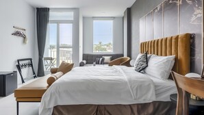 Un dormitorio moderno con una cama grande, un espacio para sentarse y vistas a la ciudad.