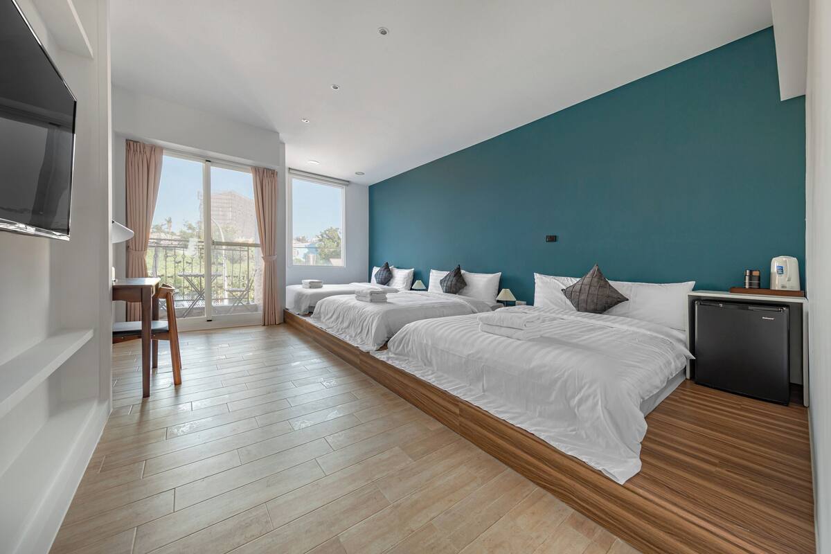 A hotel room with two beds, a TV, a desk, and a chair.