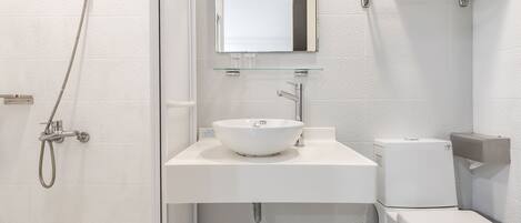 A modern bathroom with a shower, sink, and toilet.