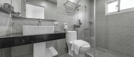 A modern bathroom with a large sink, toilet, and shower area.
