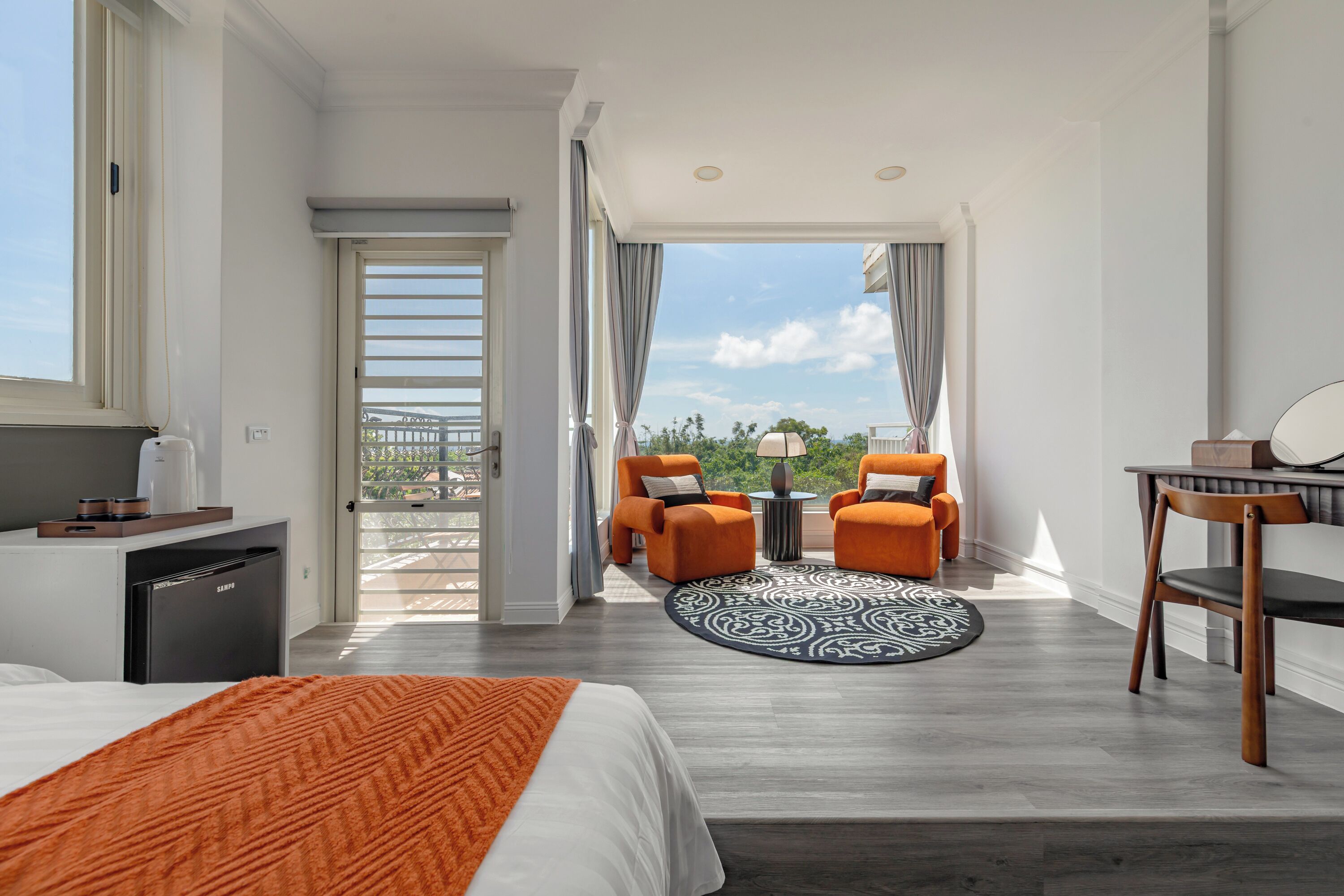 Una habitación de hotel moderna con cama, escritorio, dos sillas y un balcón con vistas.