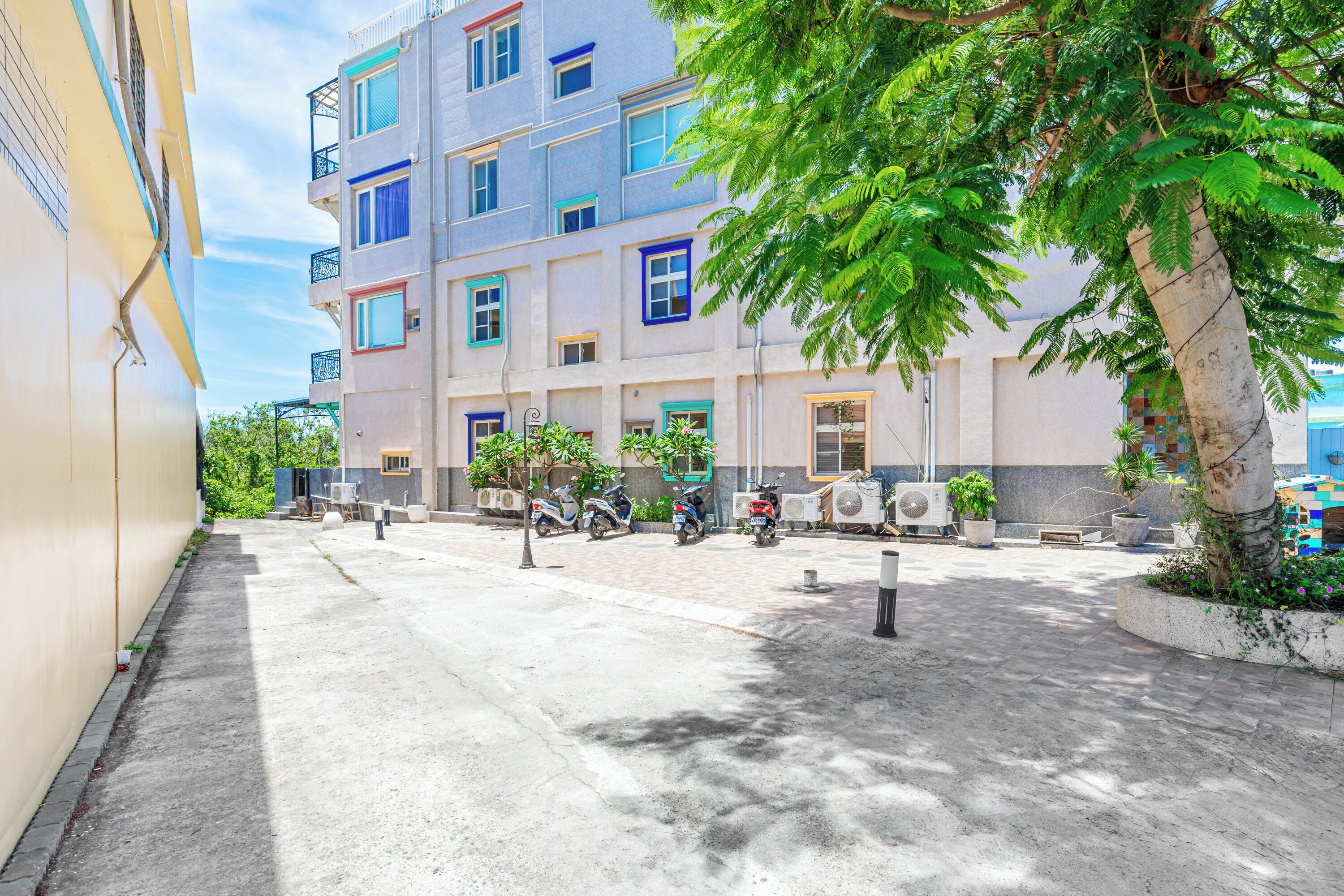 Un immeuble à plusieurs étages doté de balcons, d’une cour pavée et de scooters garés.