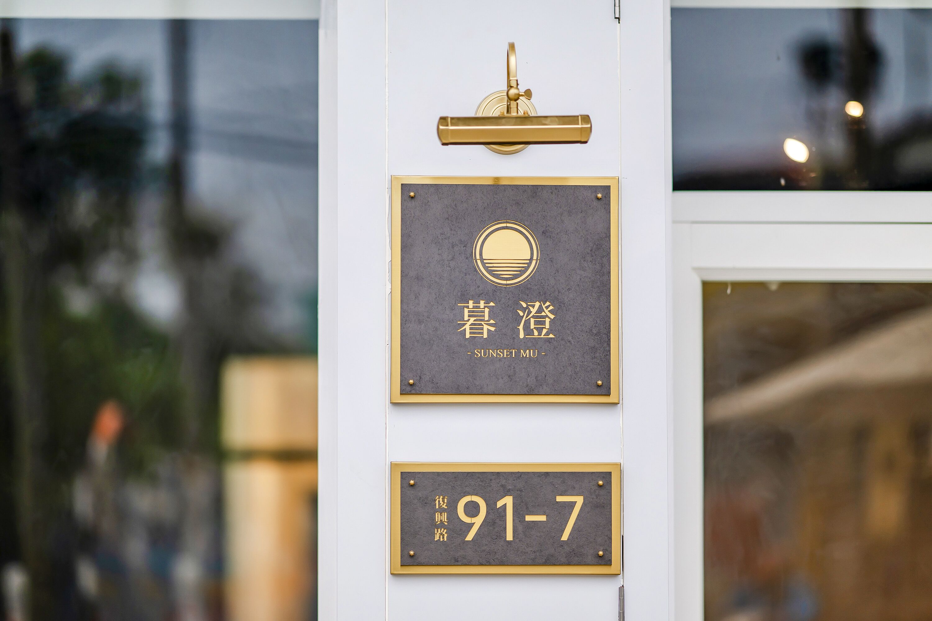 L’entrée d’un hôtel, avec une enseigne indiquant le numéro de chambre 91-7 et le nom « SUNSET MU ».