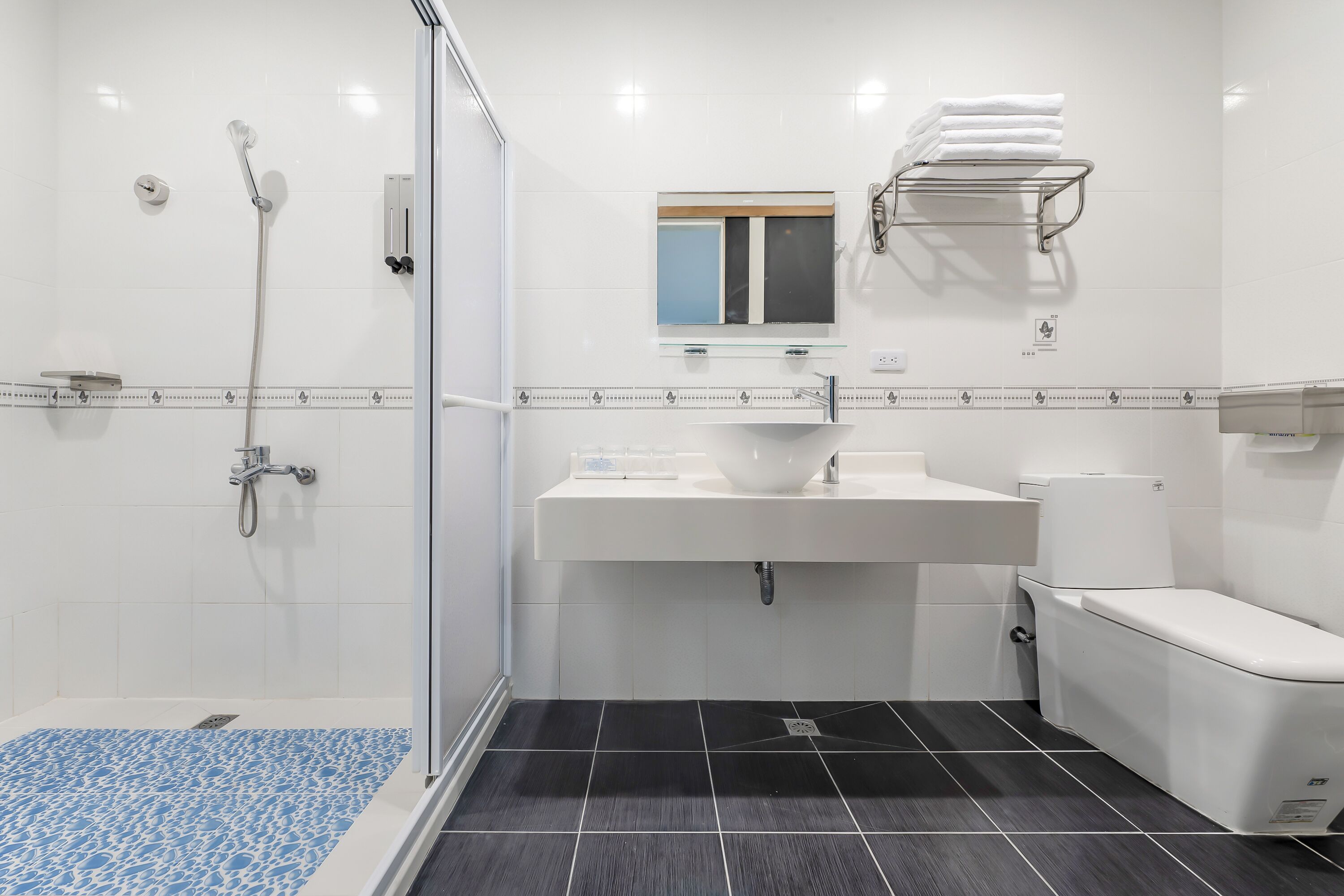 A modern bathroom with a glass shower enclosure, a white sink, and a toilet.