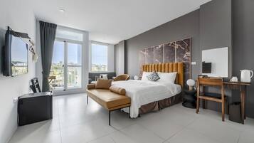 A modern hotel room with a large bed, a desk, and a sofa.