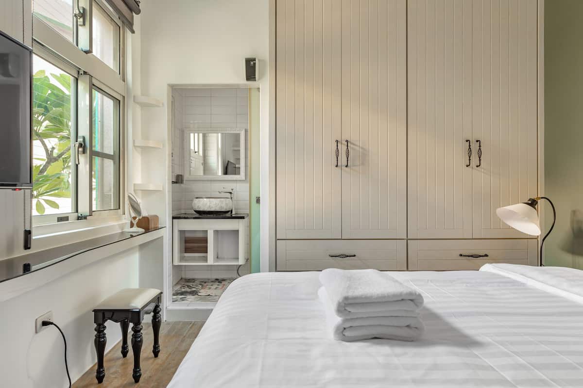 A bedroom with a bed, a TV, a window, and a wardrobe.