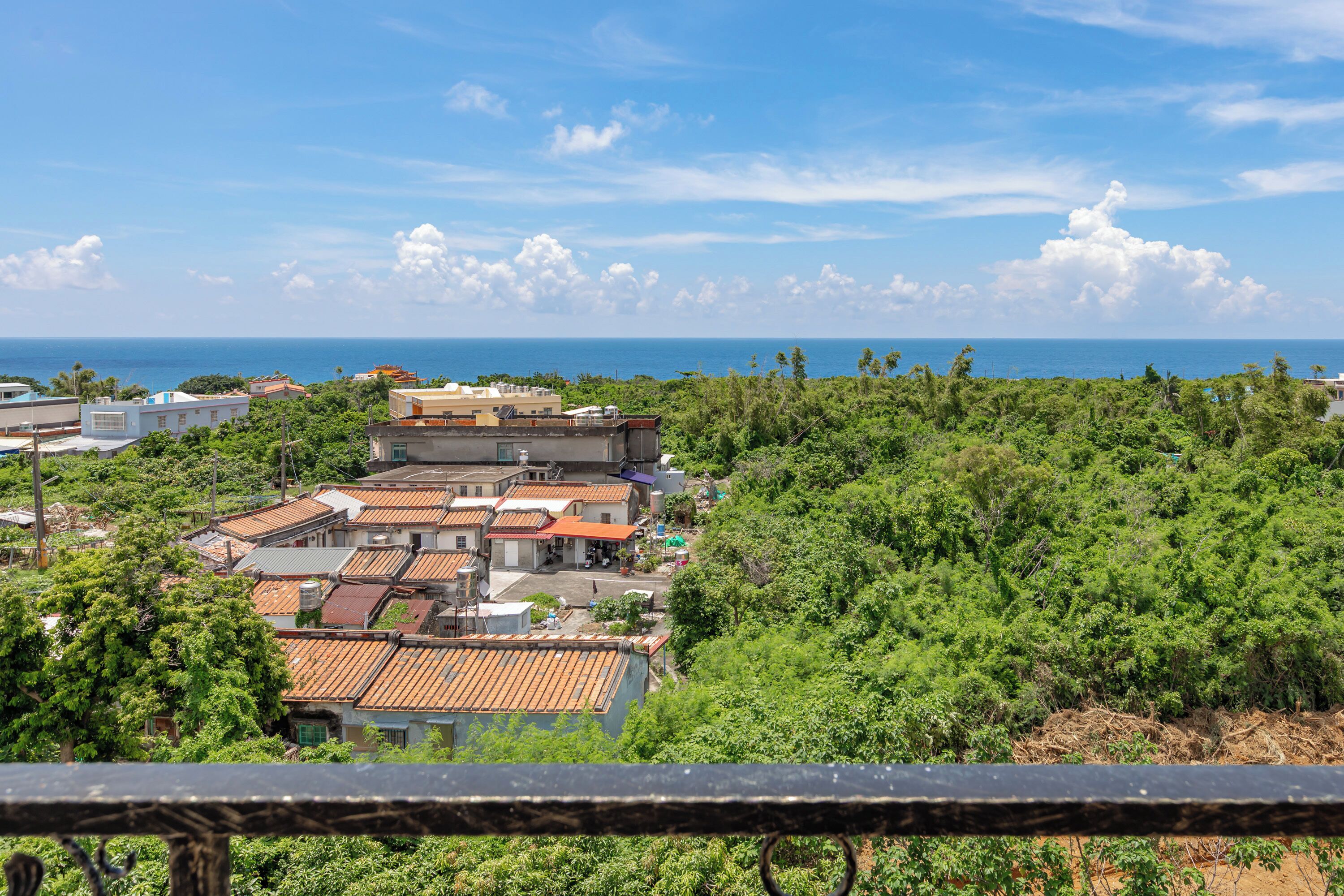 A coastal residential area with terraced houses and dense greenery.
