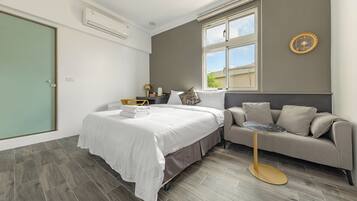 Quarto moderno com cama, sofá, mesa redonda pequena e janela.