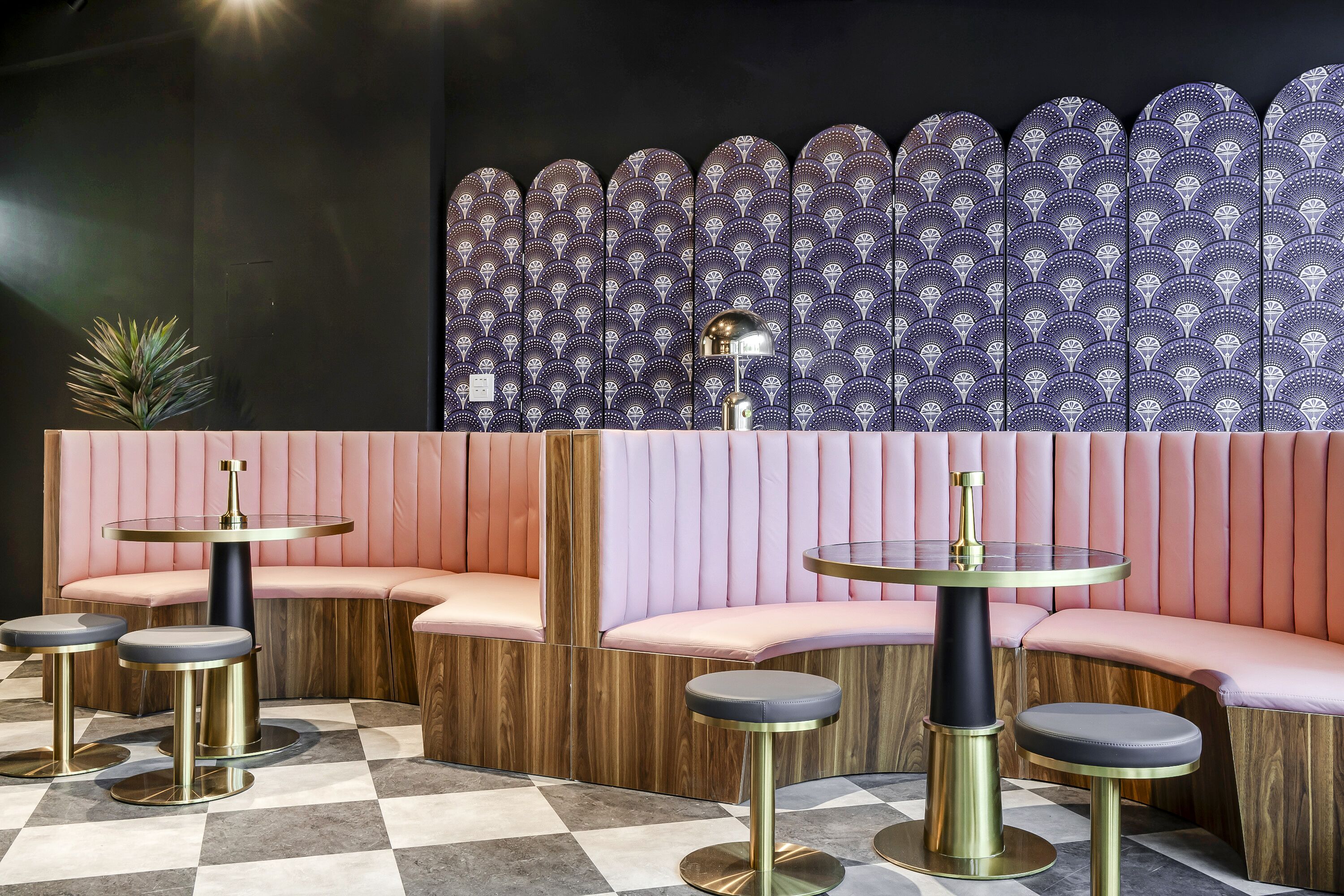 A modern interior with pink cushioned seating and gold-toned tables.