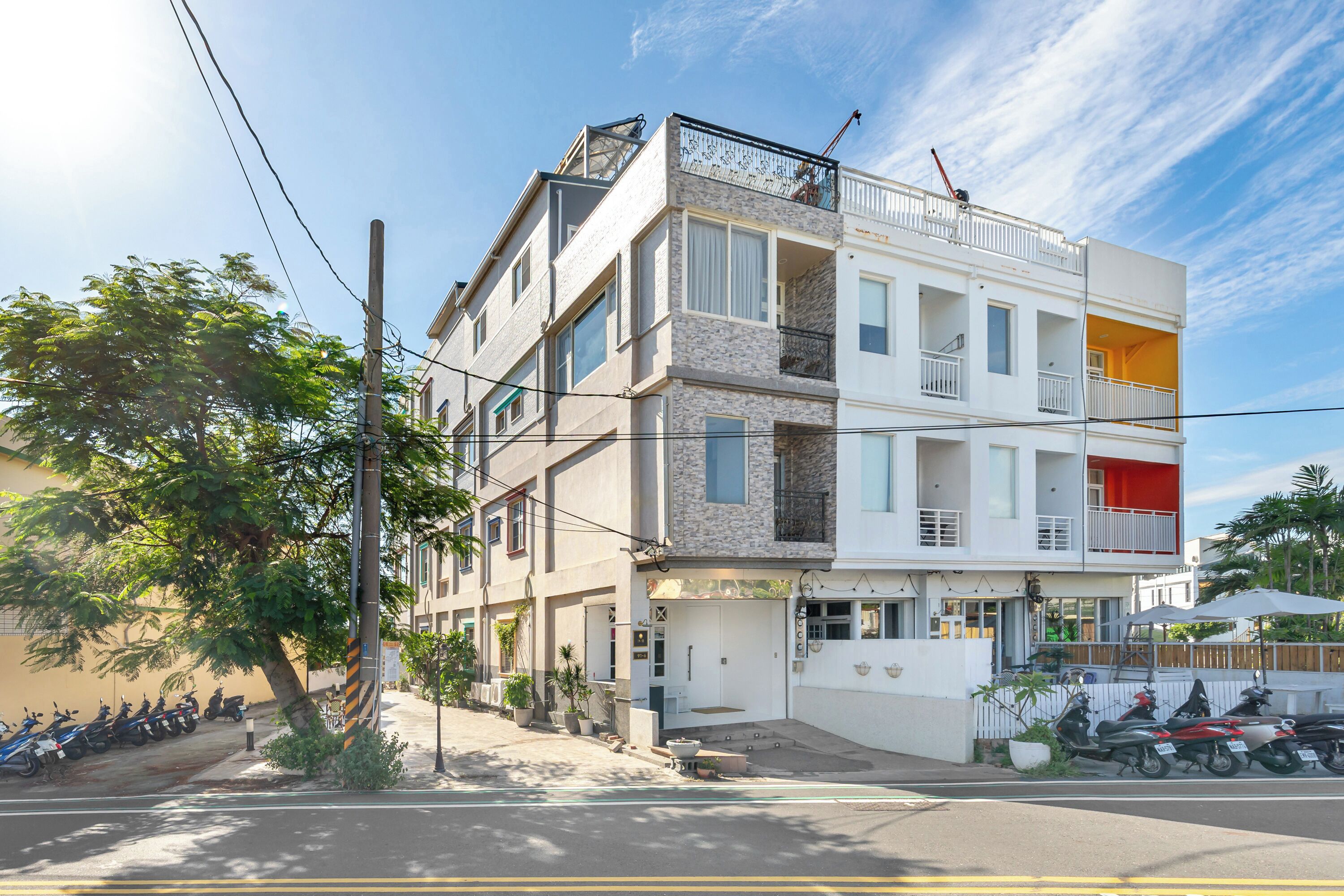 Un immeuble à plusieurs étages doté de balcons, d’une entrée au niveau du sol et d’un restaurant bien visible.
